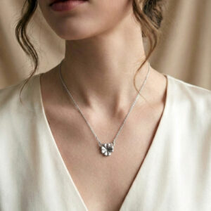 "Colgante mediano de plata de ley 925 con forma de trébol de cuatro hojas, destacando su relieve artesanal y textura orgánica sobre el escote de una modelo."